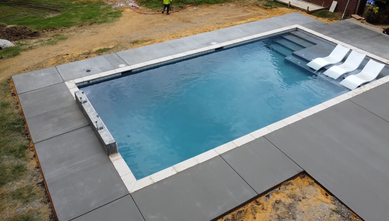 Concrete pool deck installation surrounding a residential swimming pool